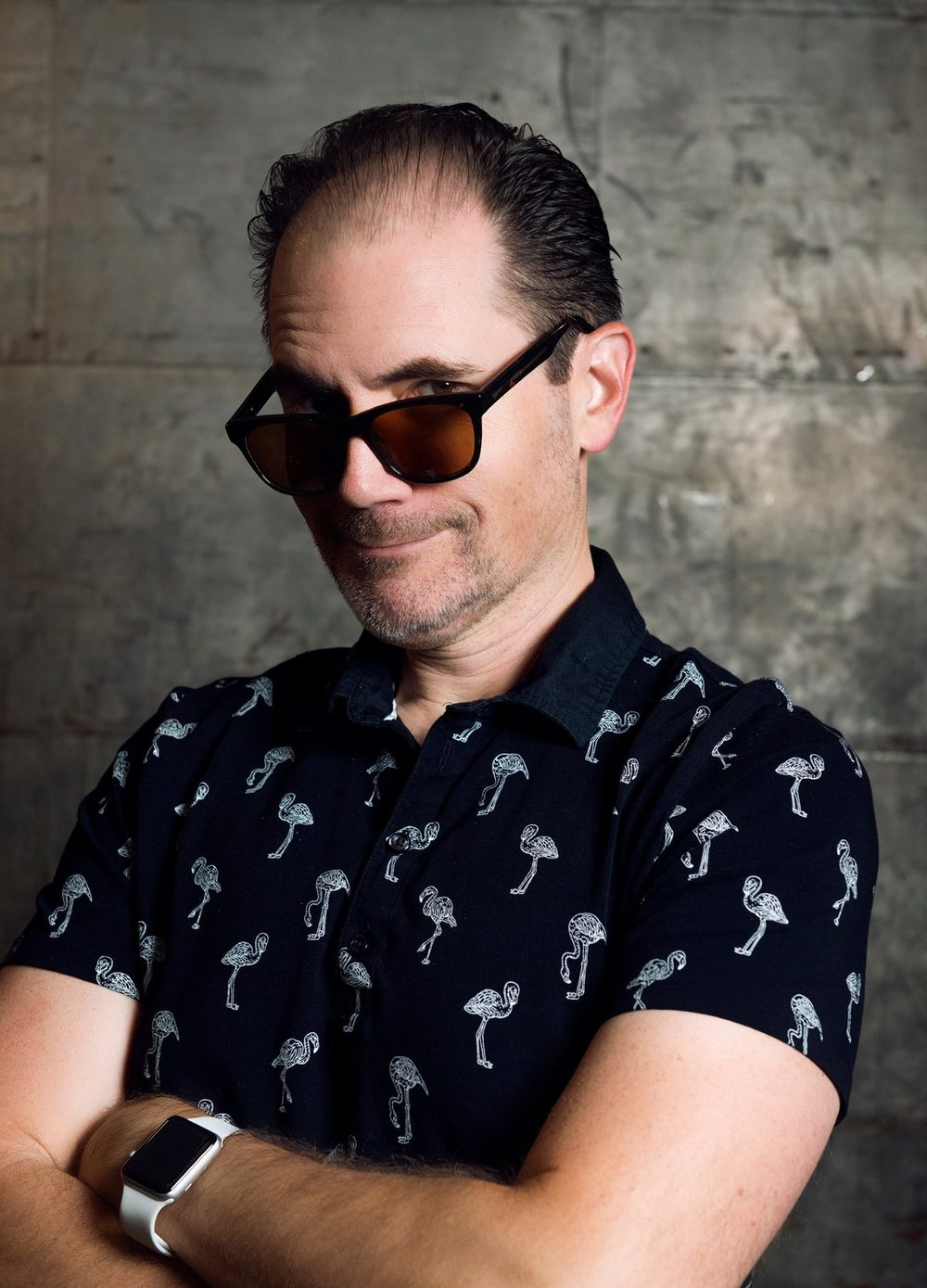 Dale in play mode, arms crossed in sunglasses and a flamingo shirt